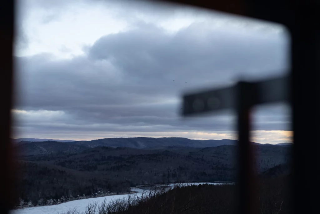 Birds fly over nearby frozen lakes and hills.